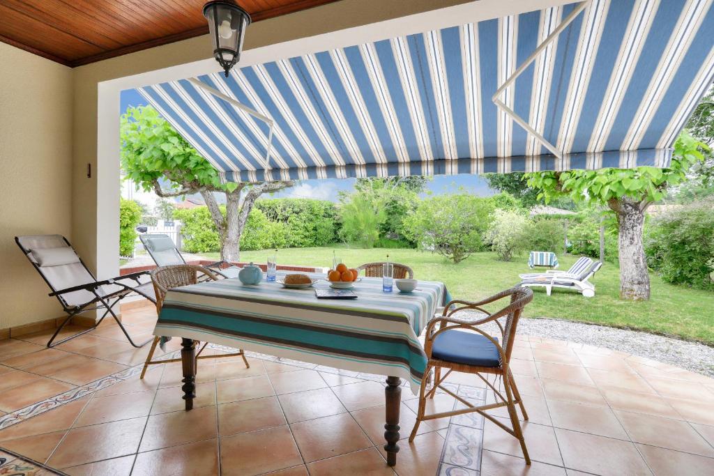 une salle à manger avec une table et des chaises ainsi qu'une terrasse dans l'établissement Maison avec jardin à 1km de la plage du Mauret, à Andernos-les-Bains