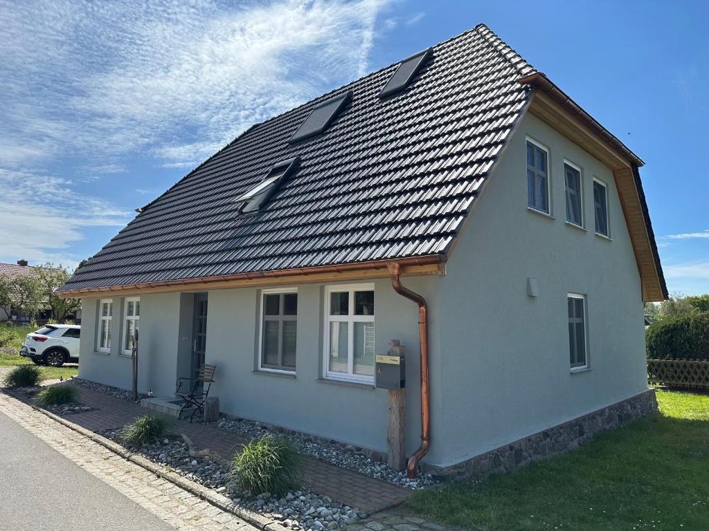 a small white house with a metal roof at Fischerhus37 FeW Jasmund in Polchow