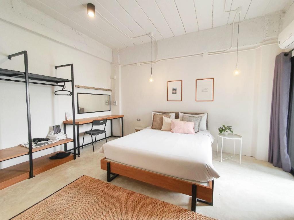 A spacious-looking bedroom with a double bed, open storage rack, desk and bright window.