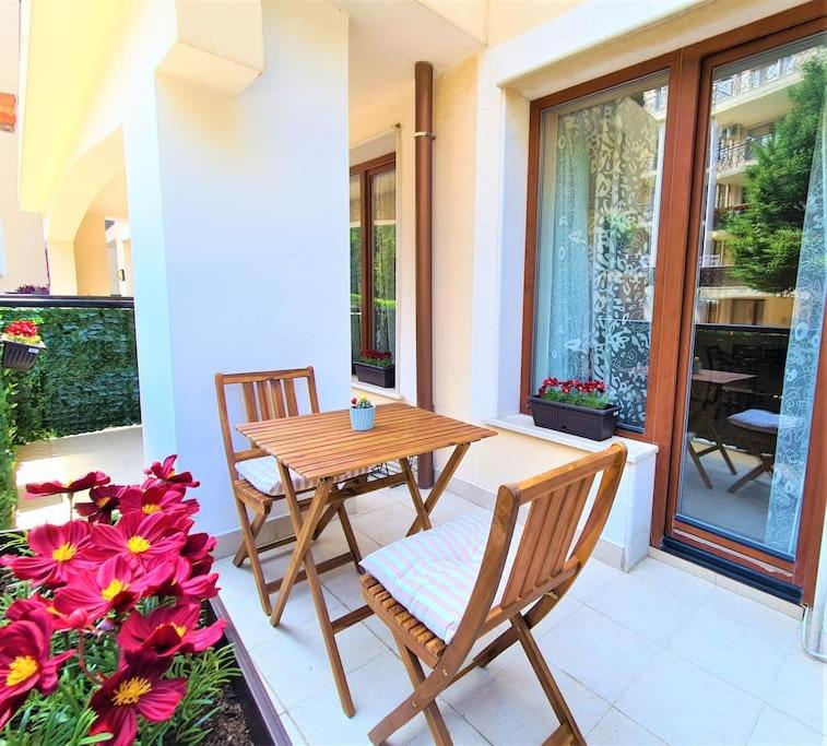 a wooden table and chairs on a patio with flowers at MATEO Golden Sands 2 in Golden Sands