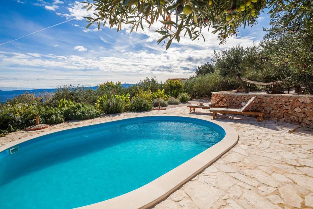 a swimming pool in a yard with a table and a bench at Holiday home Zlatni san - private heated pool in Bol