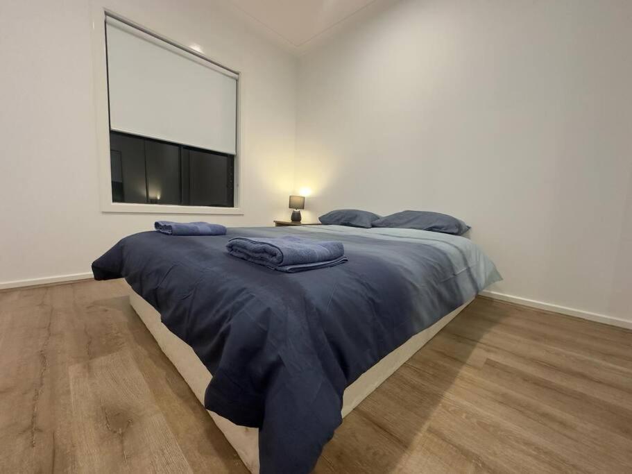 a bedroom with a large bed with blue sheets at Stockmans in Truganina