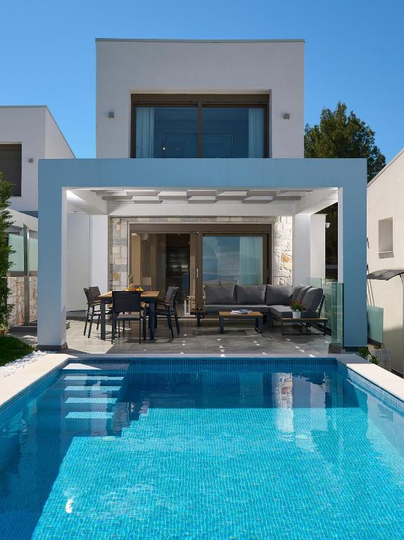 a house with a swimming pool in front of a house at Villa Paradisio 2, Pool, Sea View in Hanioti