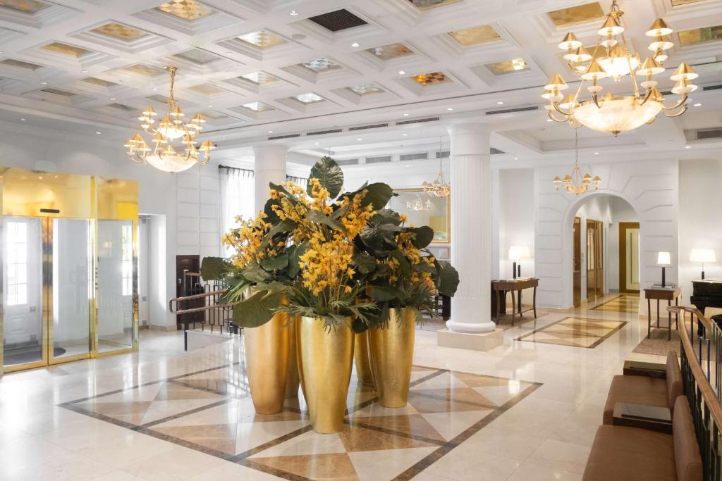 Grand Hotel Vilnius — A lobby with two large vases with flowers in it