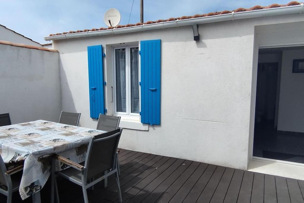 une table et des chaises sur un balcon avec volets bleus dans l'établissement Charmante maison du marché de Domino, à Les Sables Vignier