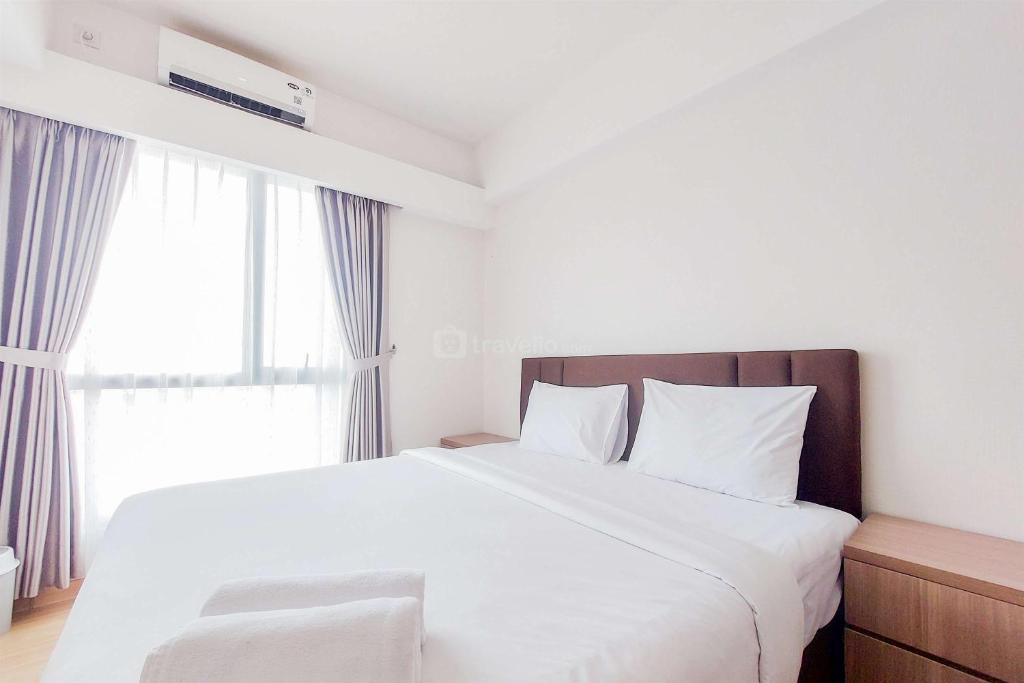 a bedroom with a large white bed with a window at Good Deal and Comfy 2BR Sky House BSD Apartment By Travelio in Tangerang