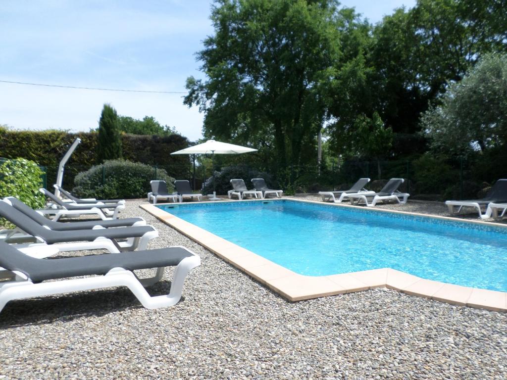 a swimming pool with lounge chairs and an umbrella at Hotel Les Oliviers in Draguignan