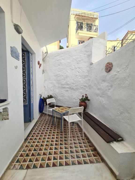patio ze stołem i krzesłami na ścianie w obiekcie Aithra -cosy studio in centre of Poros w Poros