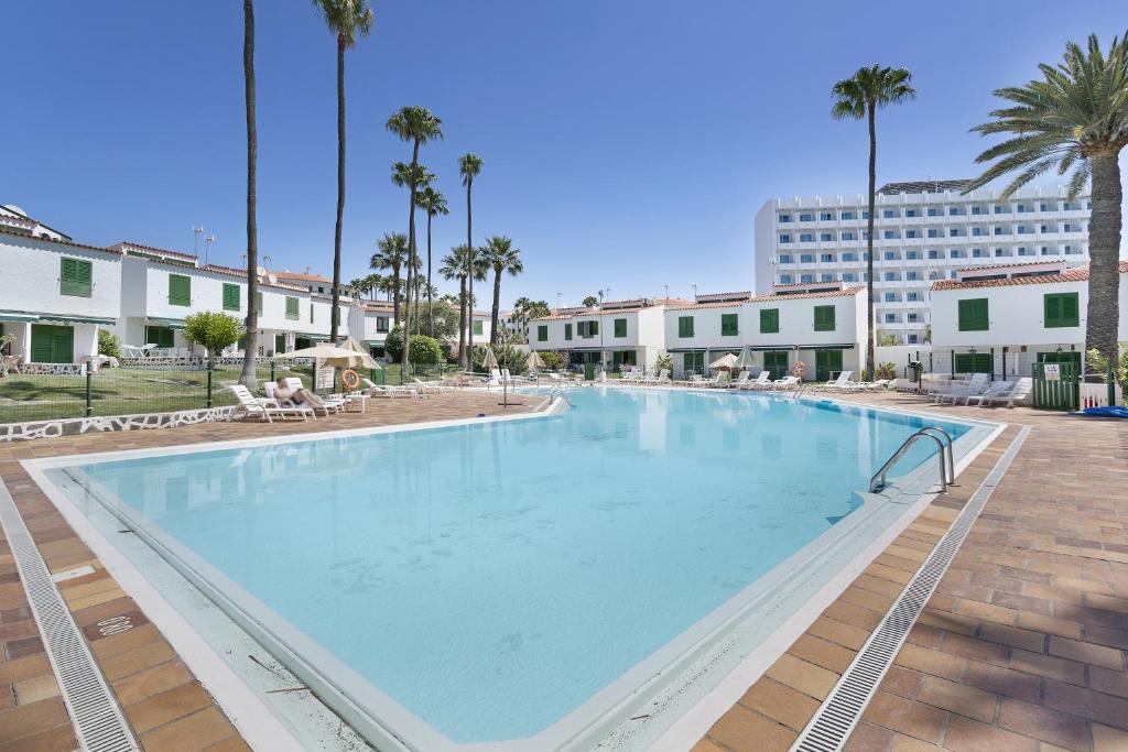 a large swimming pool in a resort with palm trees at Precioso Bungalow De Playa in Maspalomas