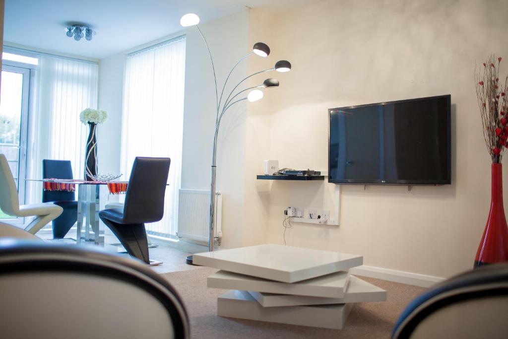 a living room with a tv and a table and chairs at Athletes Way House in Manchester