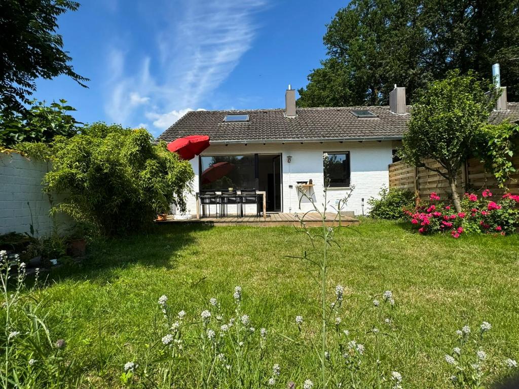 a white house with a red umbrella in a yard at Ferienhaus Ahaus in Ahaus