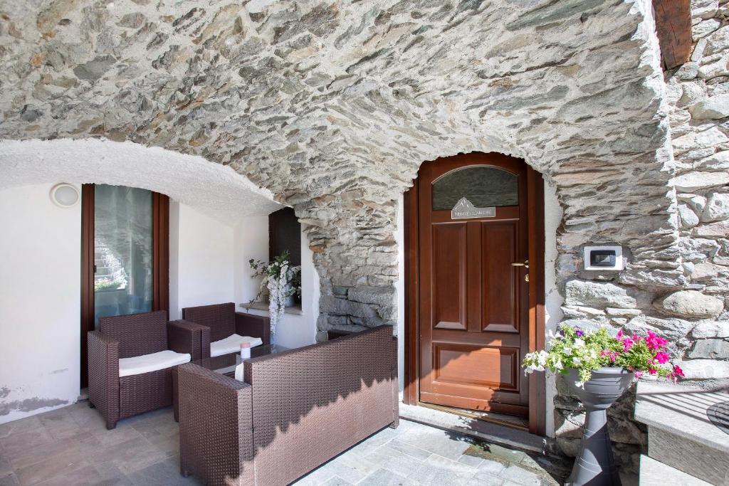 a stone building with a door and a stone wall at Maison Bebe Terre Blanche in Aosta