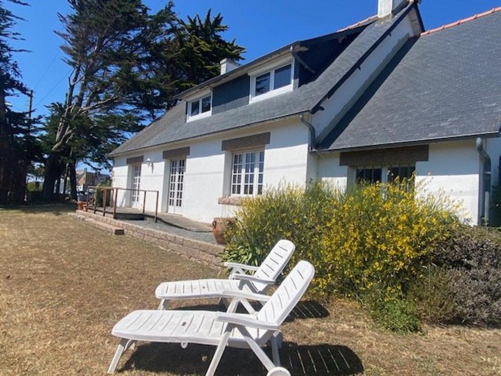 2 chaises blanches assises devant une maison dans l'établissement Maison rustique à 100m de la mer, 6 pers, jardin, Wi-Fi, parking, animaux OK, Côte de Granit Rose - FR-1-542-15, à Trégastel