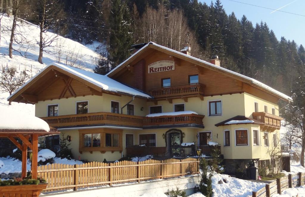 ein Haus im Schnee mit einem Zaun in der Unterkunft Pension Appartements Reithof in St. Johann im Pongau