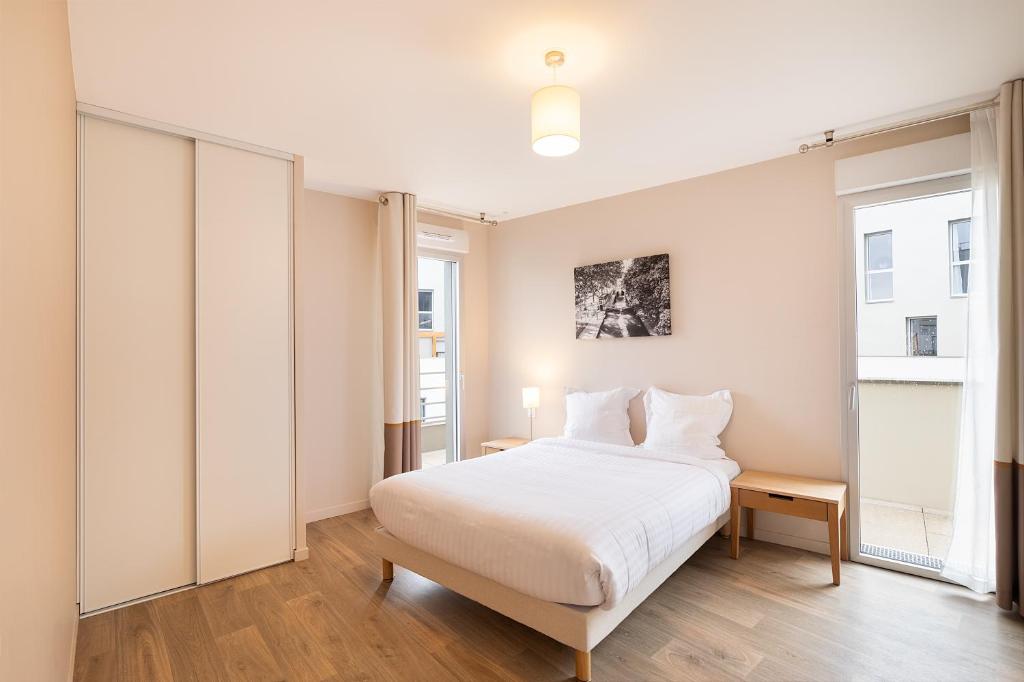 biała sypialnia z łóżkiem i oknem w obiekcie Zenao Appart'hôtels Montreuil w mieście Montreuil
