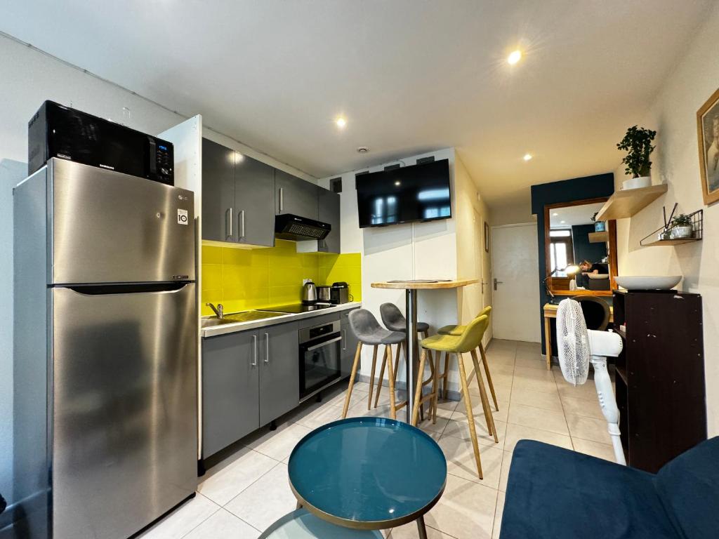 une cuisine avec un réfrigérateur en acier inoxydable et une table dans l'établissement La Loge d'Avignon - Cœur de Ville - Wifi, à Avignon