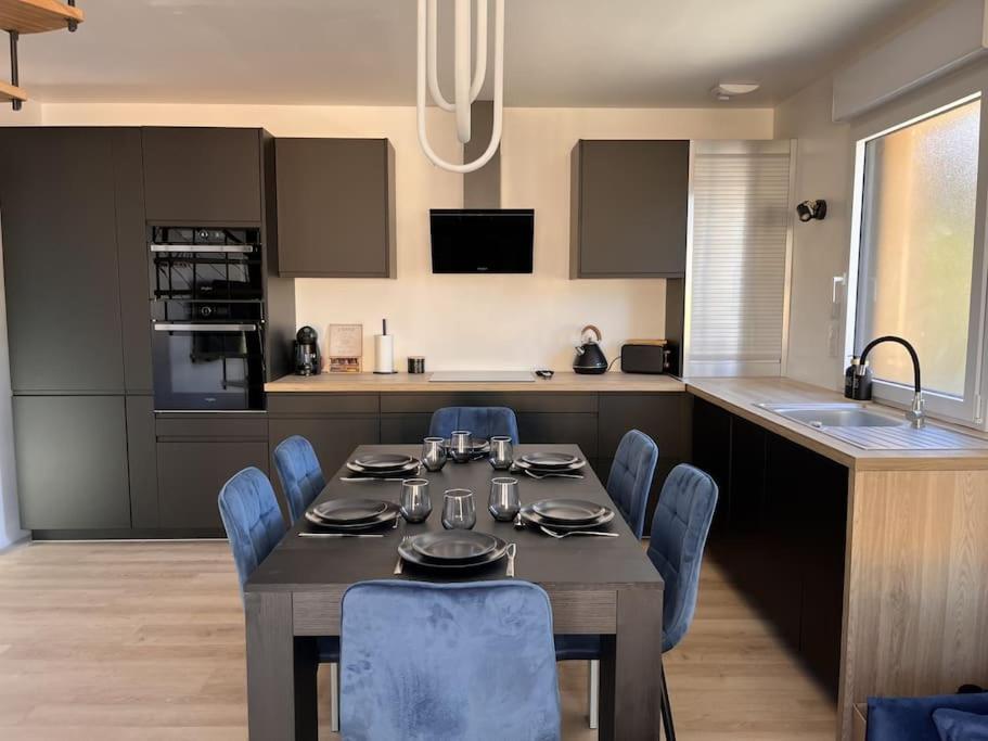 a kitchen with a table and blue chairs in a kitchen at Maison au Pays de Fontainebleau in Vulaines-sur-Seine