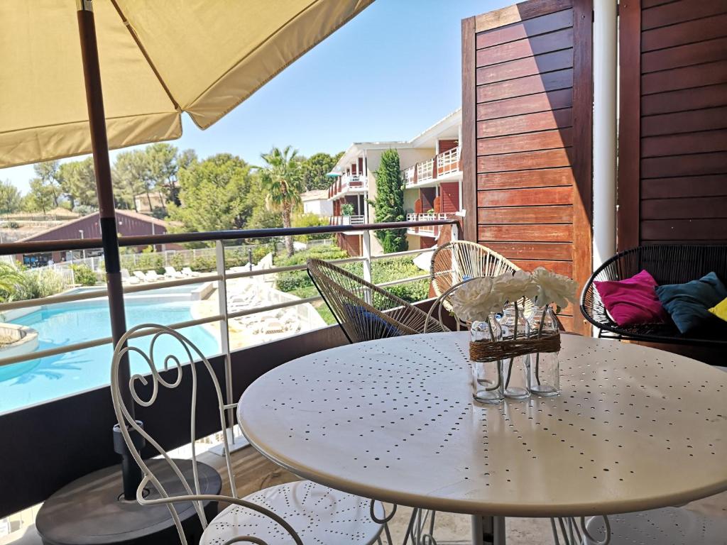 a table and chairs on a balcony with a pool at Magnifique T2 standing piscine proche mer in La Ciotat