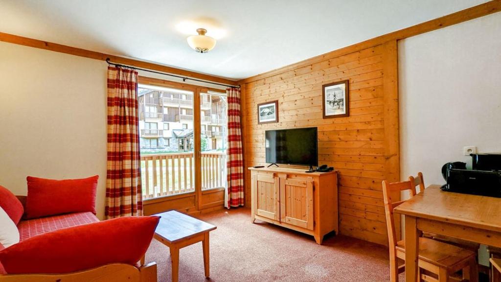 a living room with a couch and a television at Résidence Les Alpages 4 étoiles - Appartement 4 personnes - Piscine, Hammam, Sauna, Jacuzzi - ValCenis 73480 in Lanslebourg-Mont-Cenis