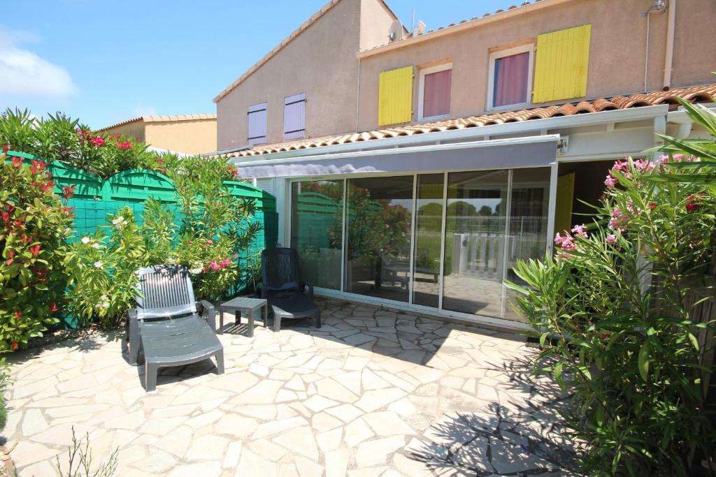 un patio avec deux chaises en face d'un bâtiment dans l'établissement Belle villa 2 chambres terrasse vue réserve naturelle dans résidence sécurisée avec piscine commune 800m de la mer LRCS50, à Portiragnes