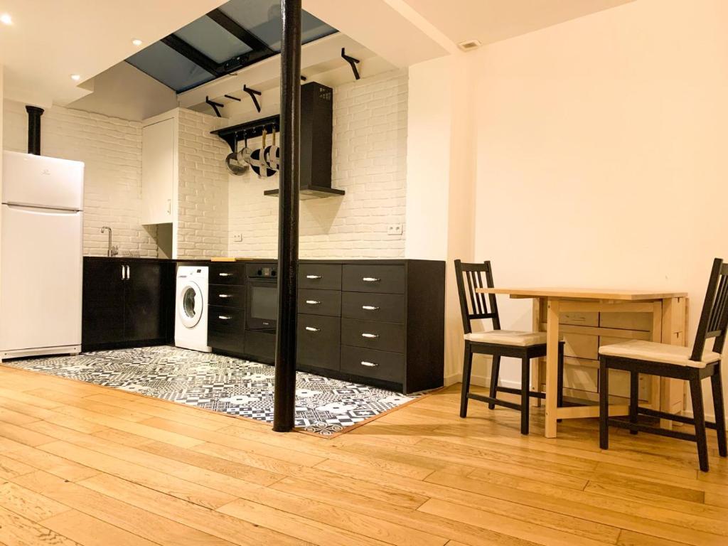 une cuisine avec des armoires noires et une table avec des chaises dans l'établissement GRAND APPARTEMENT Paris 10, à Paris