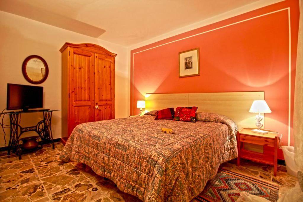 1 dormitorio con cama y pared roja en Romantico B&B, en Serra SantʼAbbondio