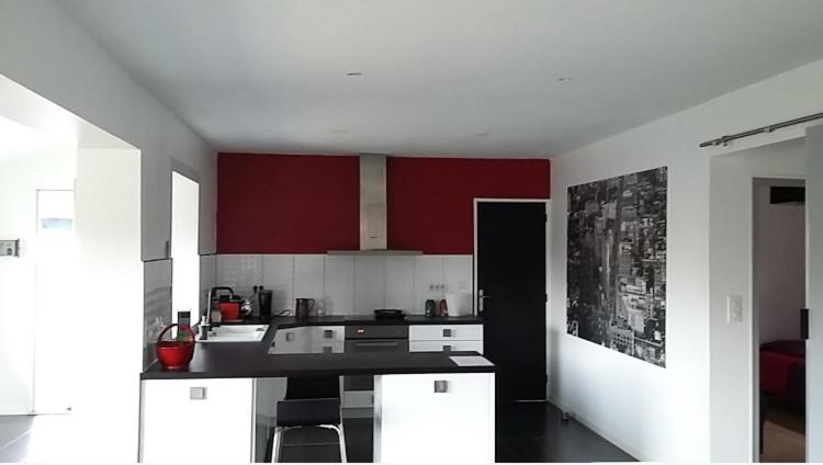 une cuisine avec des armoires rouges et un comptoir noir dans l'établissement Villa Tarnos au calme, à Tarnos