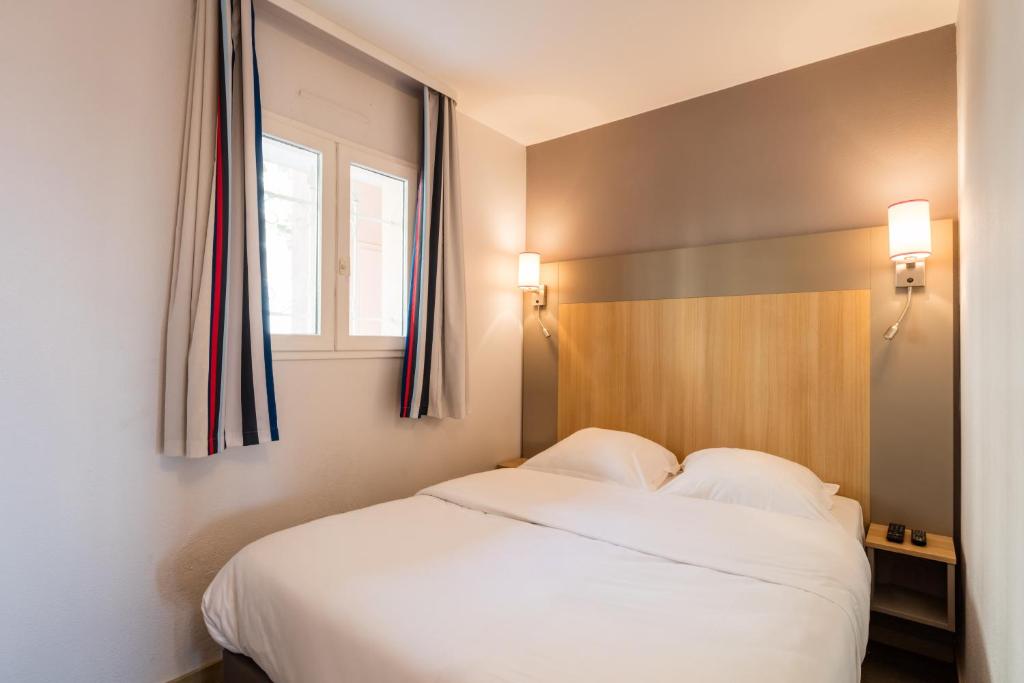 a bedroom with a white bed and a window at Résidence Pierre & Vacances l'Ange Gardien in Villefranche-sur-Mer