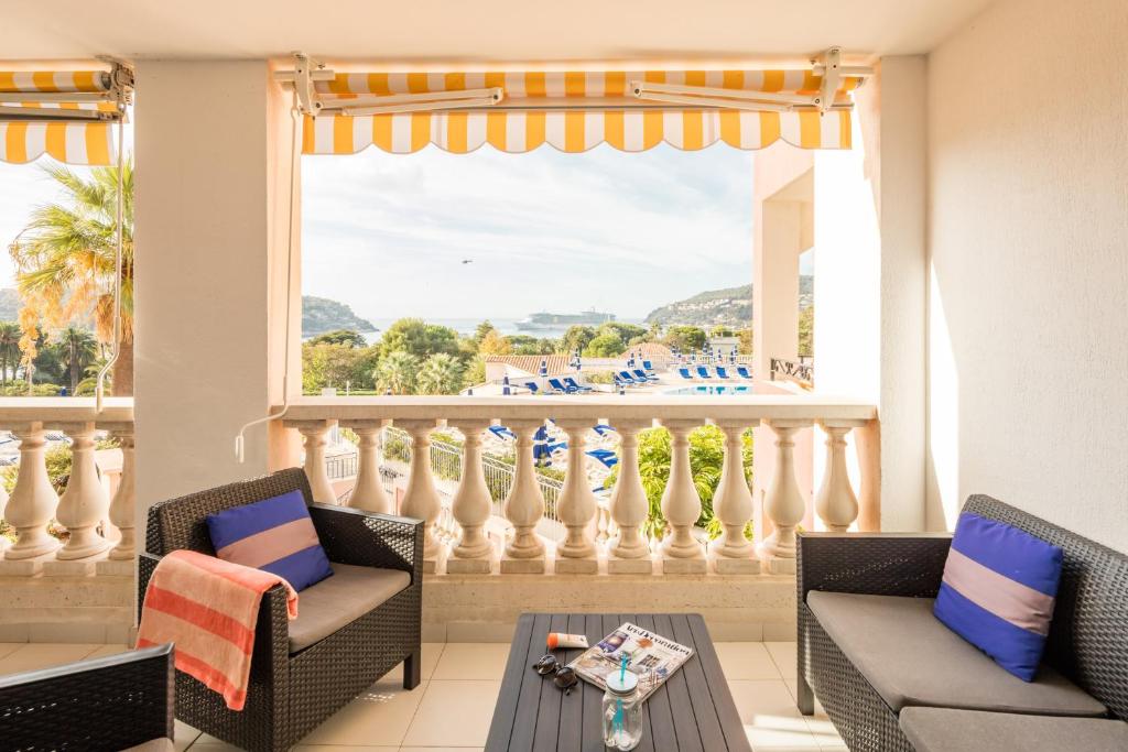 a balcony with chairs and a table and a window at Résidence Pierre & Vacances l'Ange Gardien in Villefranche-sur-Mer