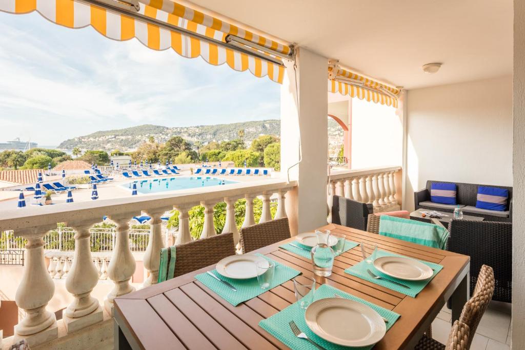 a balcony with a table and a view of a pool at Résidence Pierre & Vacances l'Ange Gardien in Villefranche-sur-Mer