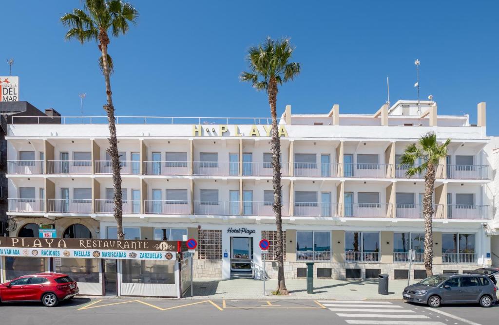 a large white building with palm trees in front of it at Hotel Playa in Peñíscola