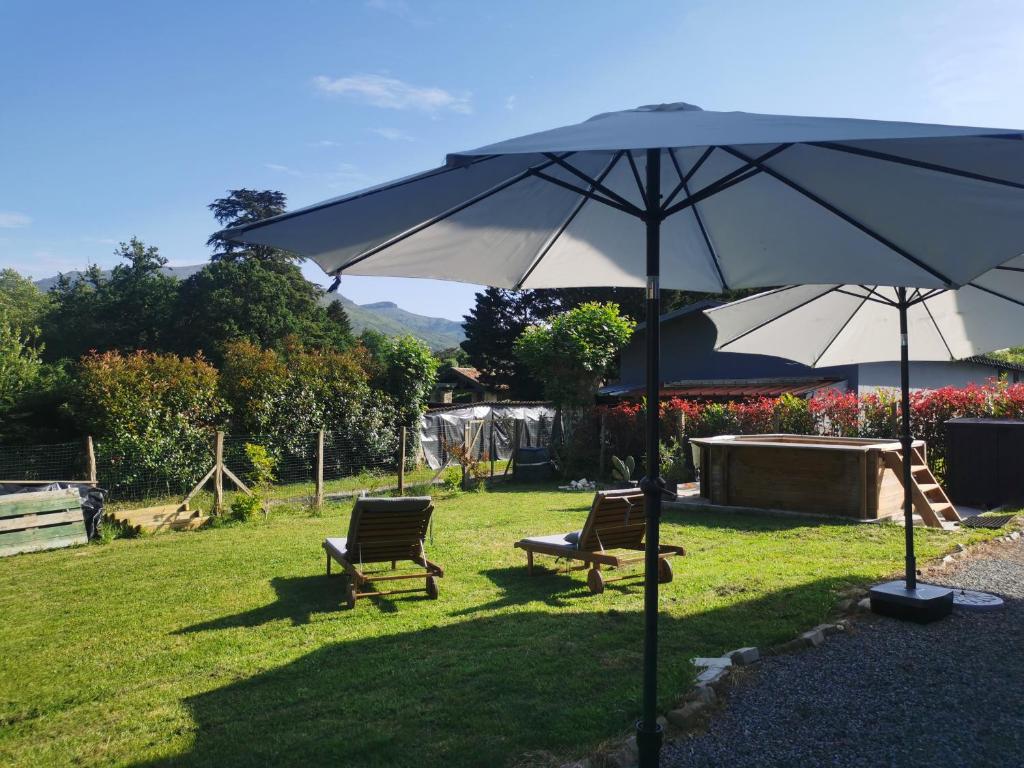 2 chaises et un parasol dans la cour dans l'établissement Charmante villa familiale au calme à 15min des plages, à Ascain