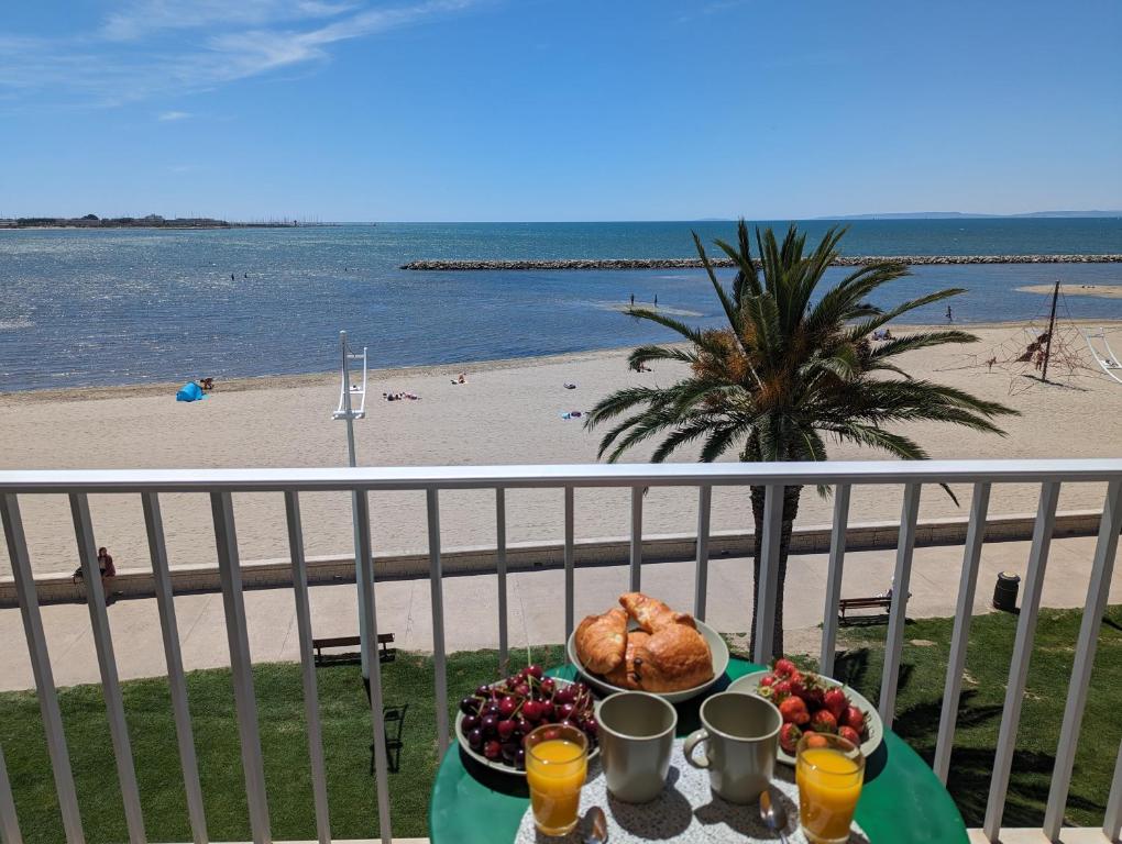 een tafel met eten op een balkon met uitzicht op het strand bij Sol-y-Days le Royal Grand studio centre ville vue mer avec parking in Le Grau-du-Roi