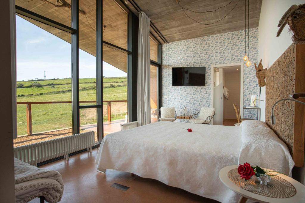een slaapkamer met een groot bed en een groot raam bij Suites Niditas in Yuso