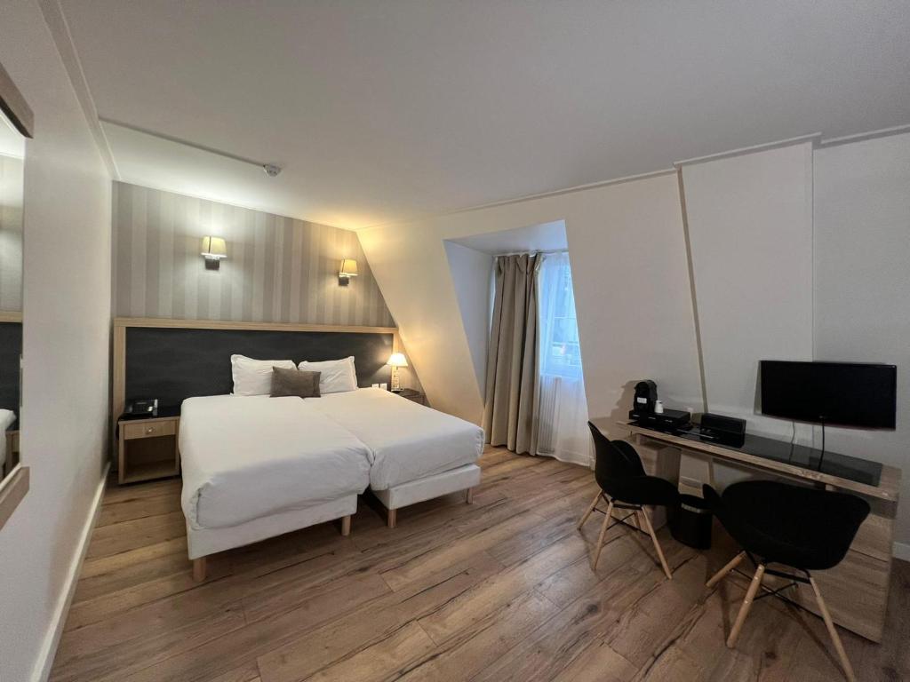 a bedroom with a bed and a desk with a computer at Hôtel Lebron in Paris