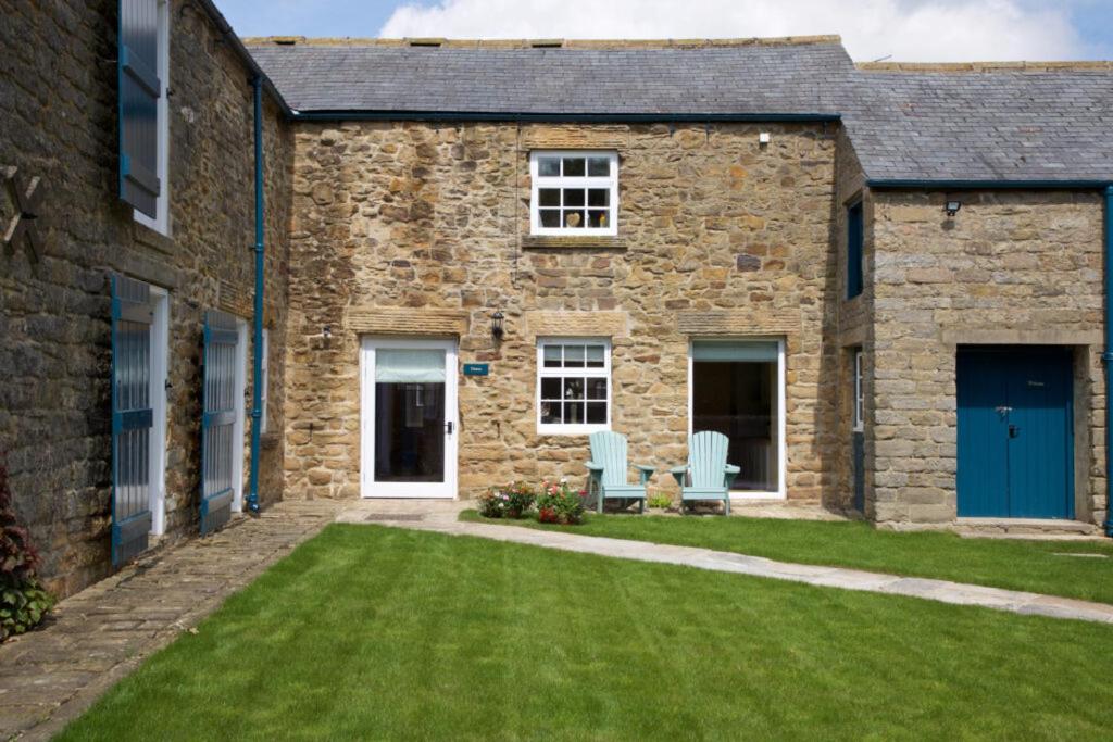 ein Steinhaus mit zwei blauen Stühlen im Hof in der Unterkunft Dunsa Cottage Bakewell Peak District in Bakewell