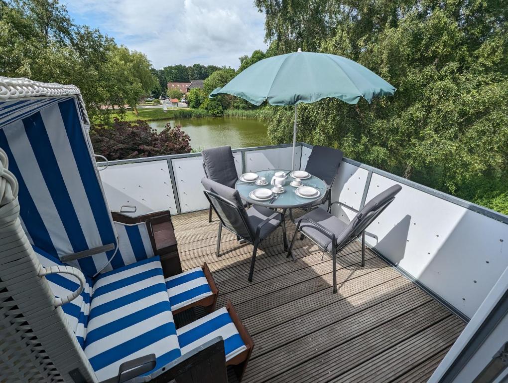a deck with a table and chairs and an umbrella at FeWo Oldeoog OG - Horumersiel in Horumersiel