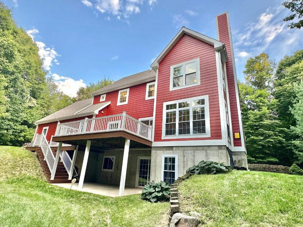 a red house with a deck on a lawn at Redbud Retreat in Centerville