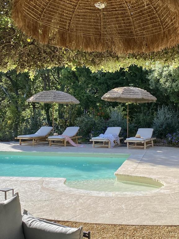- une piscine avec 2 chaises longues et des parasols dans l'établissement Nouveauté Exceptionnelle Très belle villa au pied du Mont Ventoux, à Bédoin