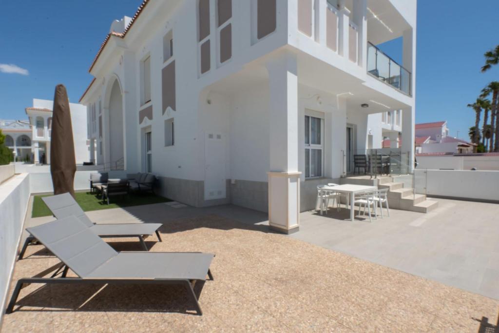 a patio with lounge chairs and a building at Helgafell Superior Courtyard Suite in Ciudad Quesada