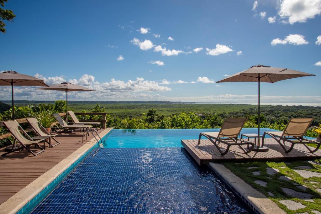 a pool with chairs and umbrellas on a deck at Manacá Pousada Parque in Arraial d'Ajuda