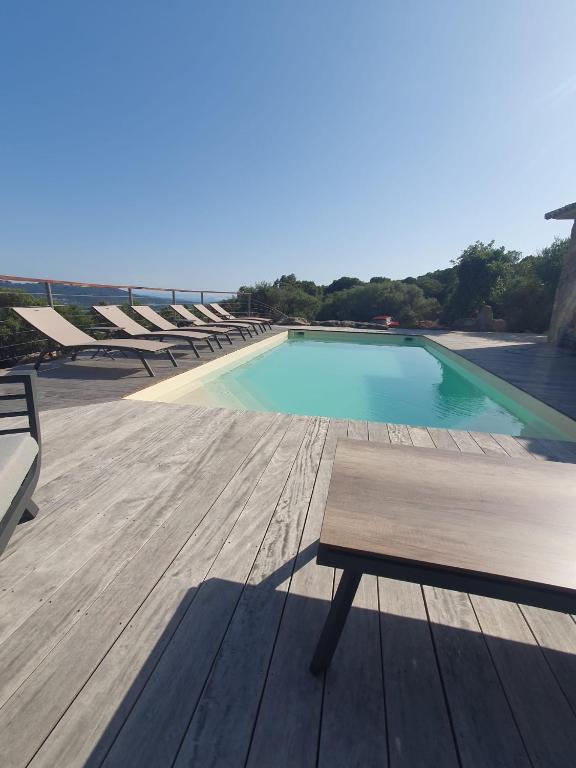 - une piscine avec des chaises et un banc sur une terrasse dans l'établissement Casa Albitru, piscine, vue mer et montagne, à Figari