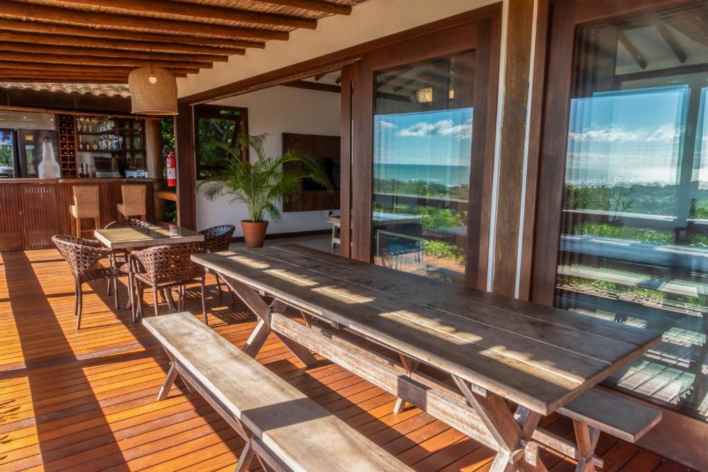 a wooden table on a deck with chairs and windows at Manacá Pousada Parque in Arraial d'Ajuda