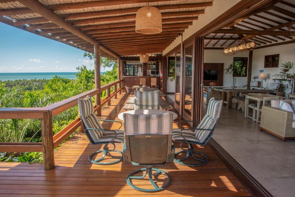a deck with chairs and a table and the ocean at Manacá Pousada Parque in Arraial d'Ajuda