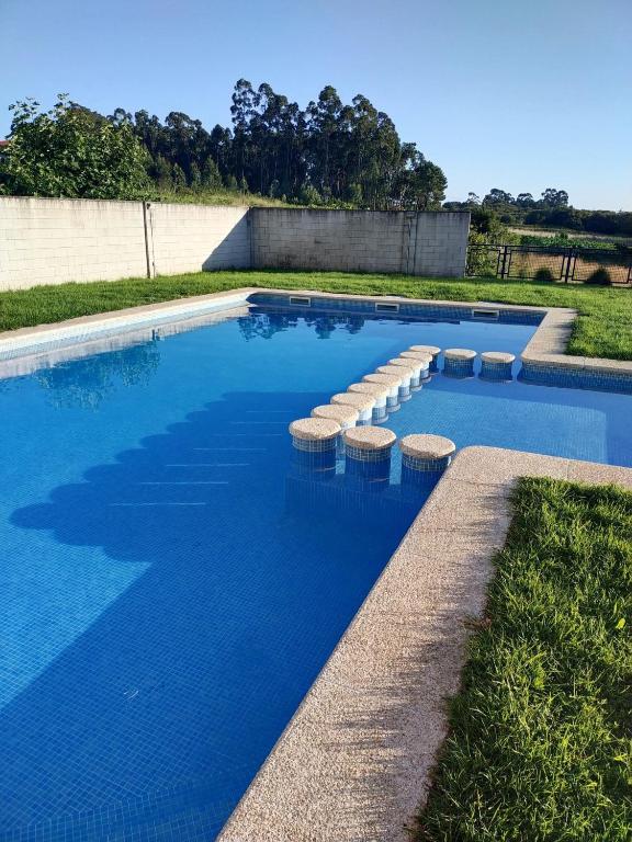 a swimming pool with stools in the middle at Edificio Fonte de Ons con piscina in Noalla