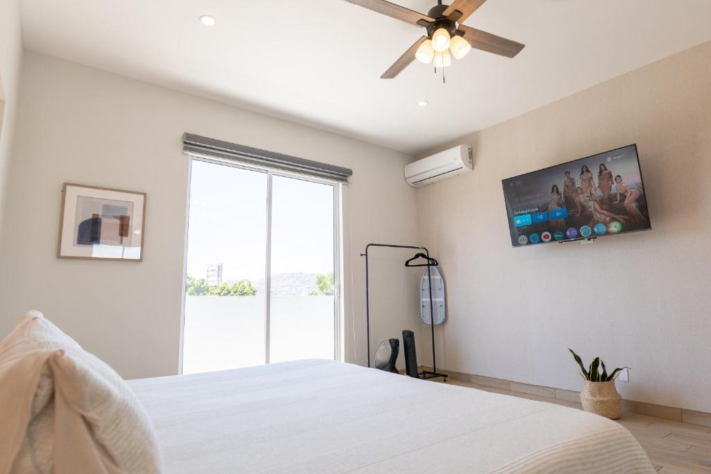 a bedroom with a white bed and a ceiling fan at New Casa Balandra with Gated Parking at Casas Sanblu in Ensenada