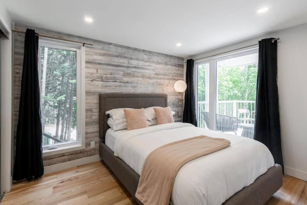 a bedroom with a wooden wall and a large bed at Modern Lodge Pool & Spa Mont-Tremblant in Mont-Tremblant