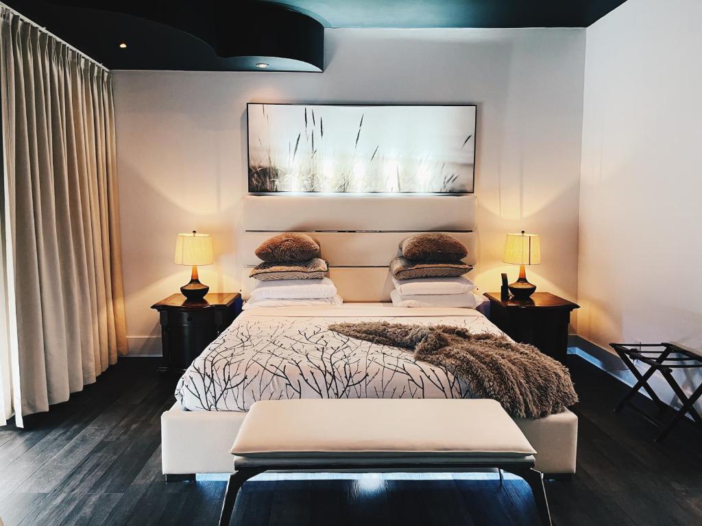 Un dormitorio con una cama y dos mesas y dos lámparas. en Hotel Kutuma, en Montreal