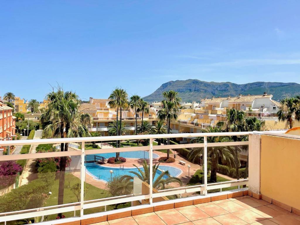 een balkon met uitzicht op een zwembad en palmbomen bij Dúplex Jardines de Denia I in Denia