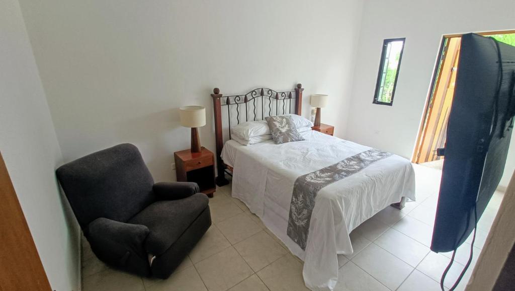 ein Schlafzimmer mit einem Bett und einem Stuhl in der Unterkunft Casa Cecilia in Cozumel